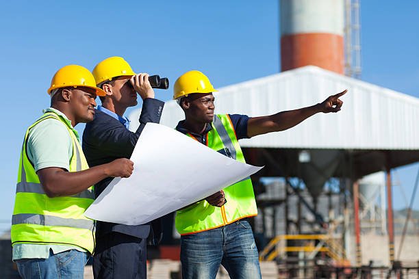 Engineers and client reviewing project layout blueprints on site